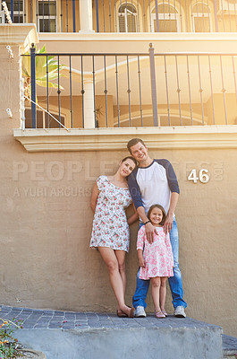 Buy stock photo Homeowner, portrait and real estate with family on wall of home together for growth or investment. Step, smile or happy with mother, father and girl outdoor at residential property for moving house