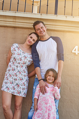 Buy stock photo Love, portrait and real estate with family on wall of home together for growth or investment. Mortgage, smile or happy with mom, dad and daughter outdoor at residential property for moving house