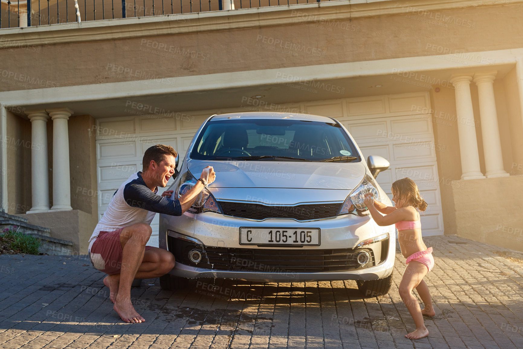 Buy stock photo Shot of a father and daughter having fun while washing a car