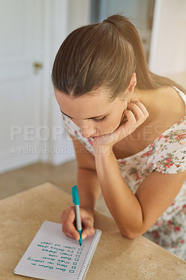 Buy stock photo Shot of a young woman writing a list of chores