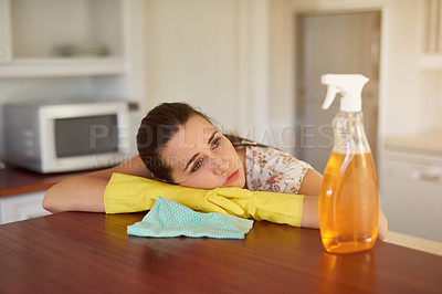 Buy stock photo Shot of a tired looking young woman leaning on a kitchen countertop
