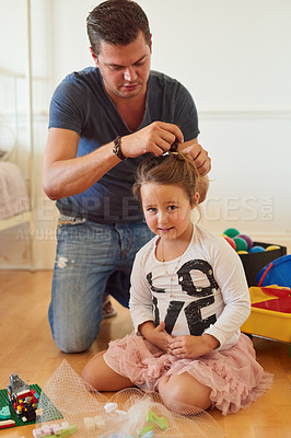 Buy stock photo Shot of a father styling his daughter's hair at home
