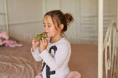 Buy stock photo Child, toy and girl kissing frog in bedroom for fairytale, happiness or playing in family home. Kiss, pretend and young kid on bed with object in playroom for having fun, playful or game in apartment
