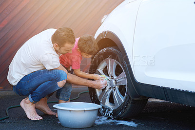 Buy stock photo Full length shot of a father and son washing the wheel of a car together