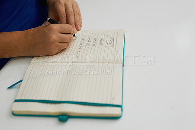Buy stock photo Shot of a person writing in a book at a table
