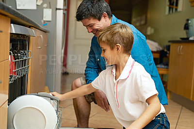 Buy stock photo Shot of a father and son busy at a dishwashing machine