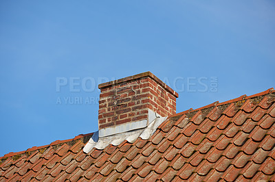 Buy stock photo Red brick chimney on the slate roof of a house outside against a blue sky with copyspace. Low angle exterior view of rural building rooftop. Architecture of chute for fireplace smoke and ventilation