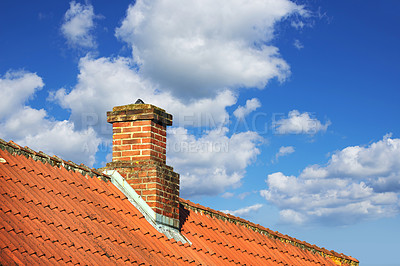 Buy stock photo A house with a red brick chimney on an asbestos slate roof outside with a blue sky background. Exterior building designed construction and architecture of a rooftop chute for fireplace smoke and heat