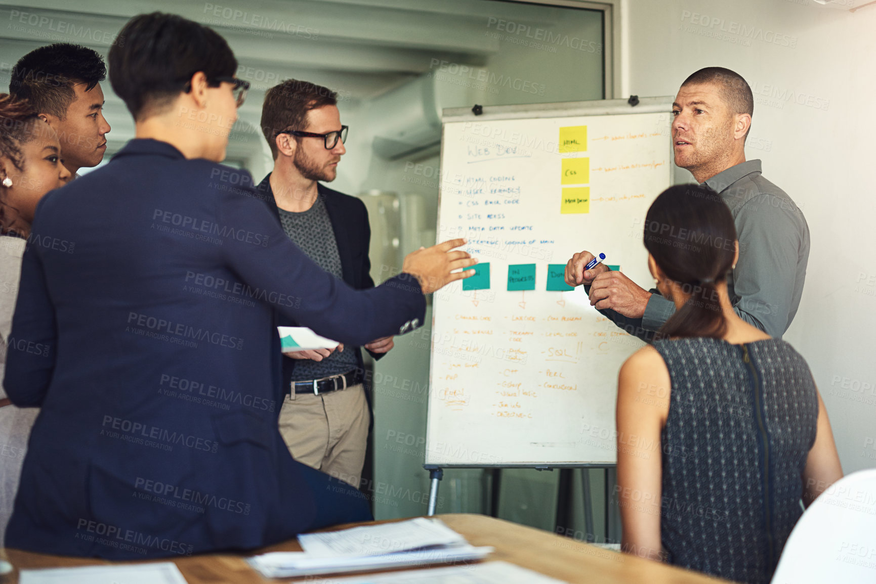 Buy stock photo Shot of a group of colleagues having a meeting together around a whiteboard in an office