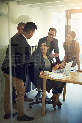 Buy stock photo Shot of a group of coworkers discussing something on a laptop during a meeting