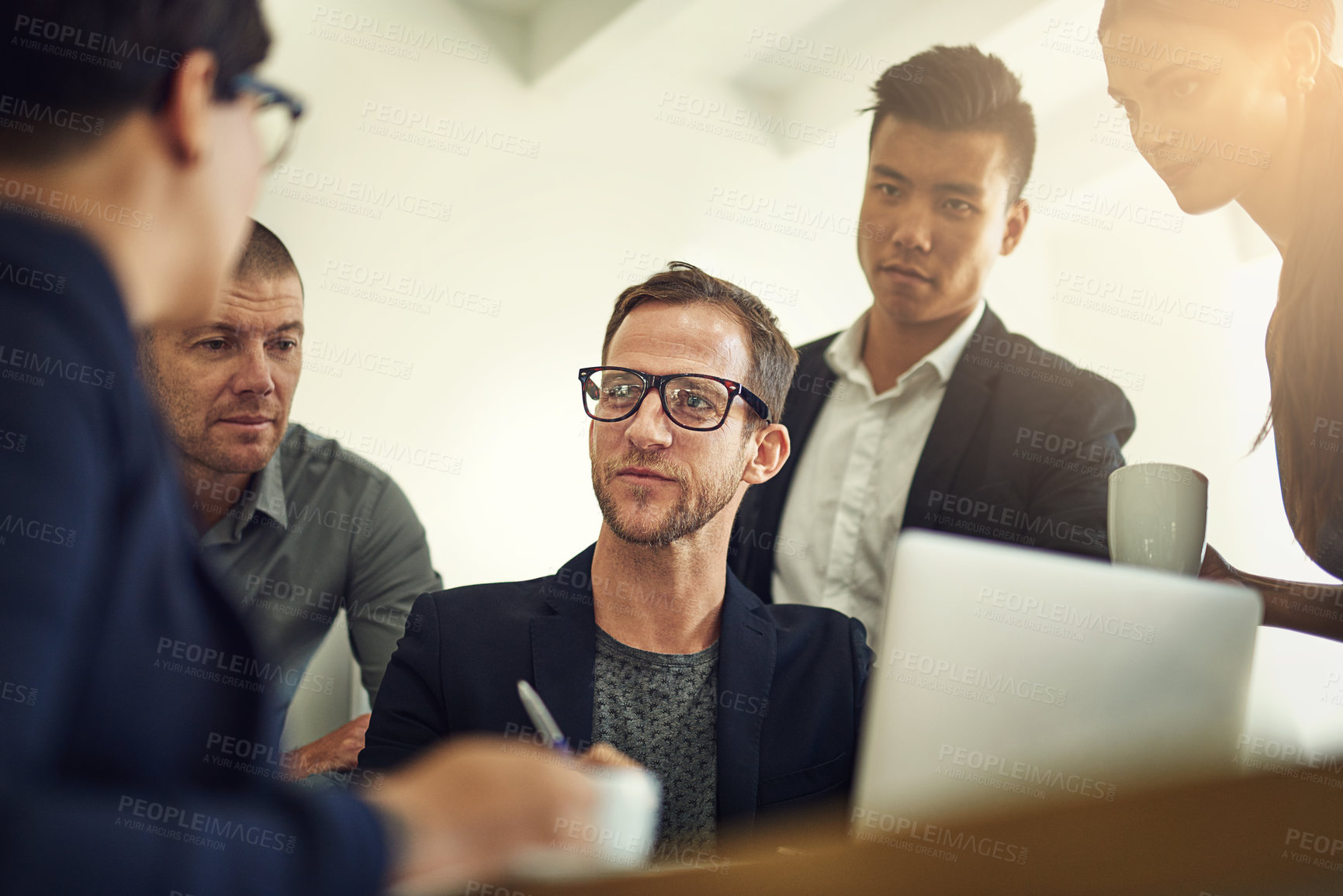 Buy stock photo Shot of a group of coworkers discussing something on a laptop during a meeting