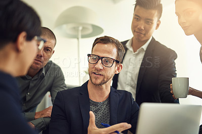 Buy stock photo Shot of a group of coworkers discussing something on a laptop during a meeting