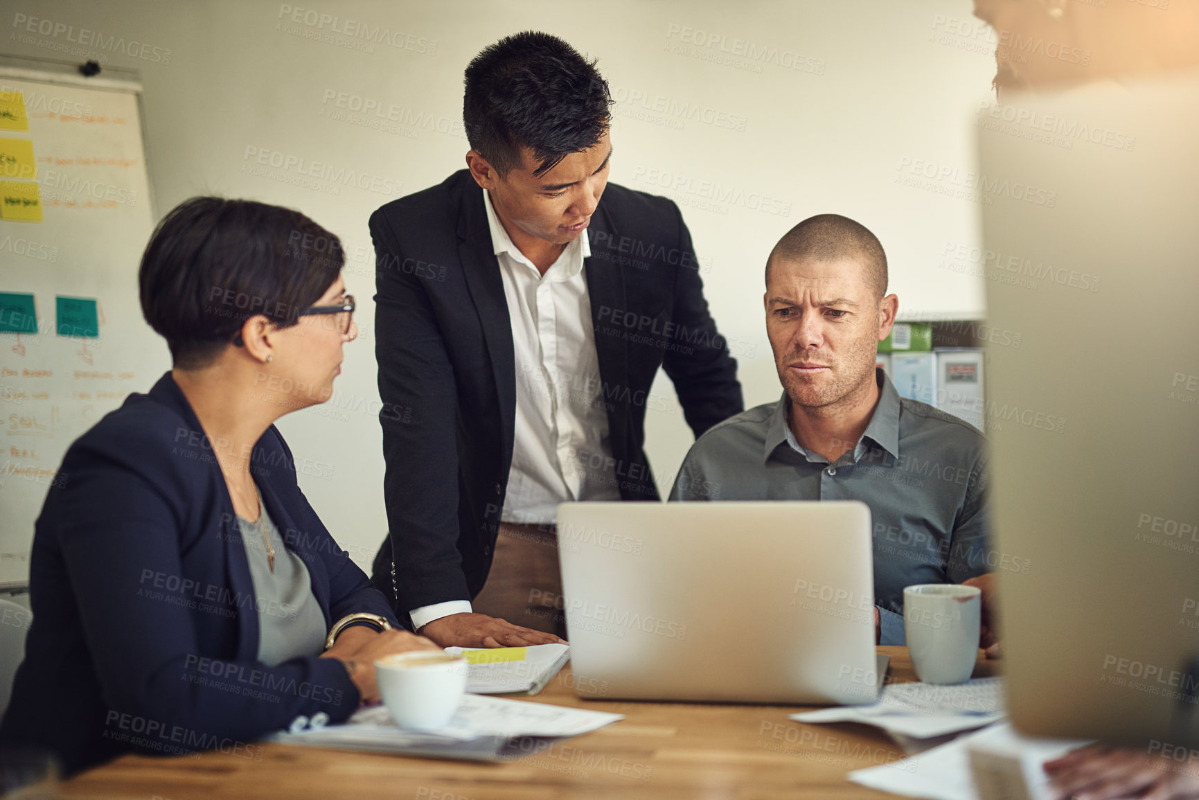 Buy stock photo Shot of a group of coworkers discussing something on a laptop during a meeting