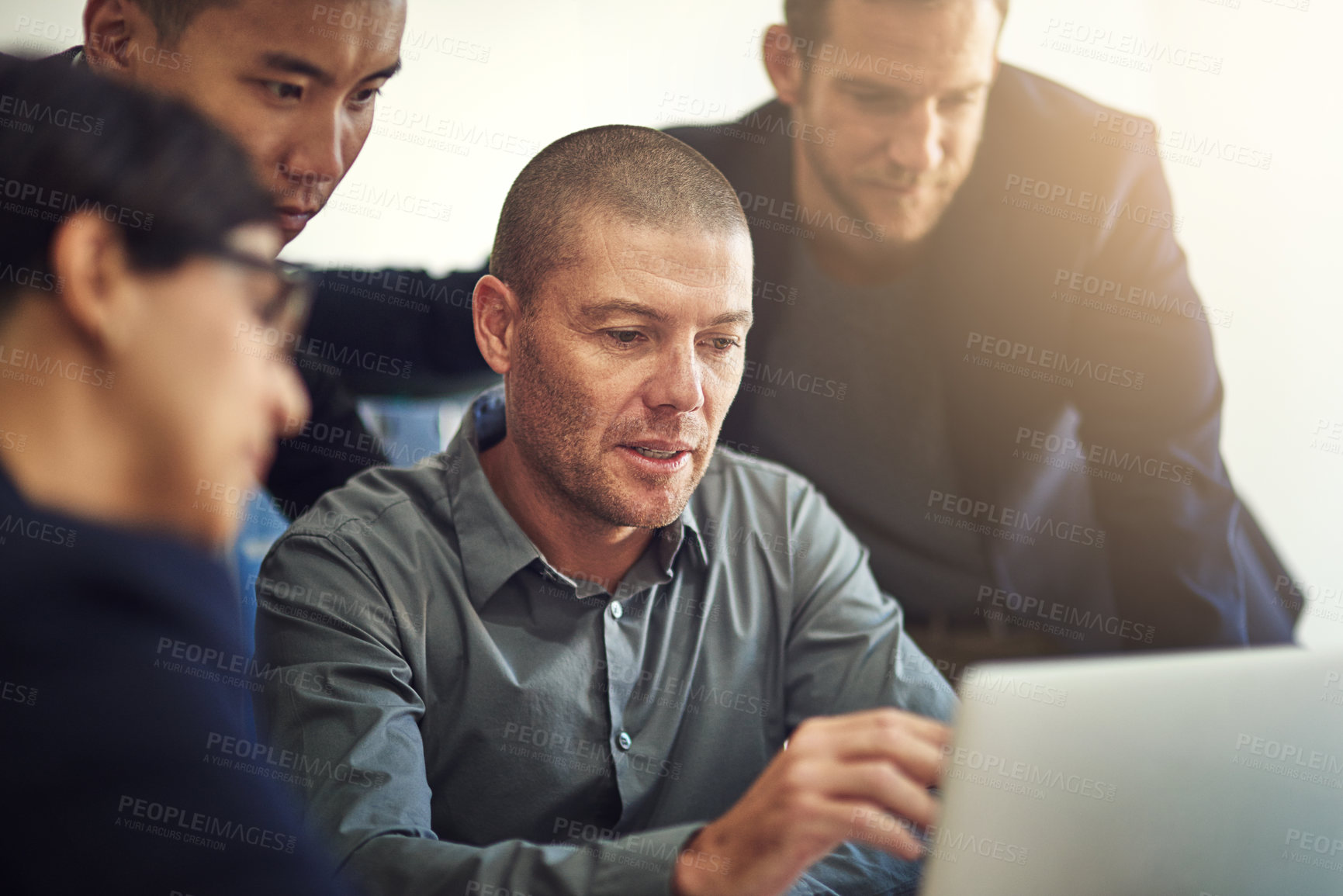 Buy stock photo Shot of a group of coworkers discussing something on a laptop during a meeting