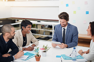 Buy stock photo Shot of businesspeople using a digital tablet in an office meeting