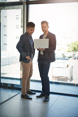 Buy stock photo Shot of two businessmen discussing something on a laptop in an office