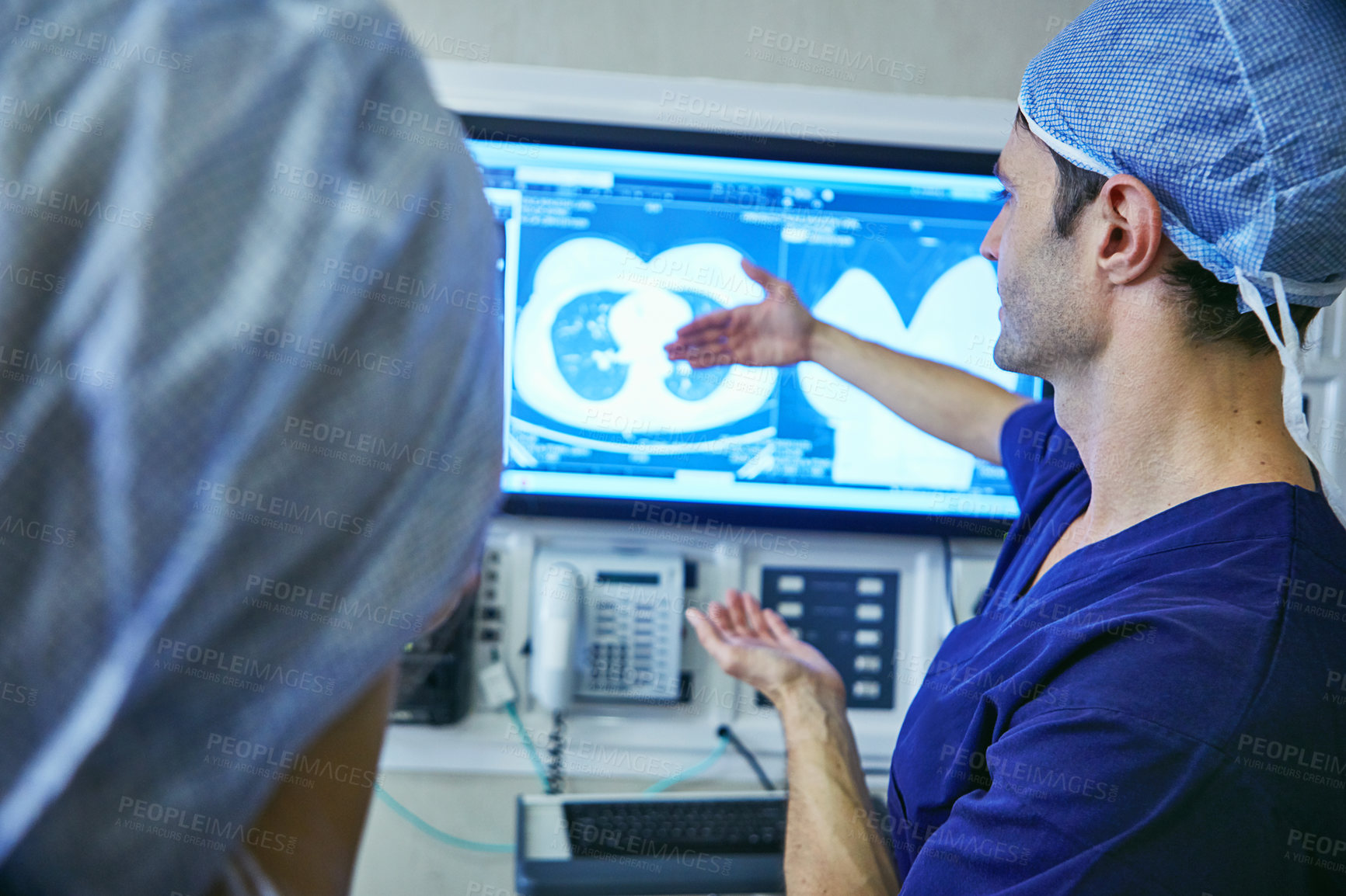 Buy stock photo Shot of a team of surgeons discussing a patient’s medical scans