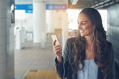 Buy stock photo Shot of a young woman listening to music on a phone in an urban setting