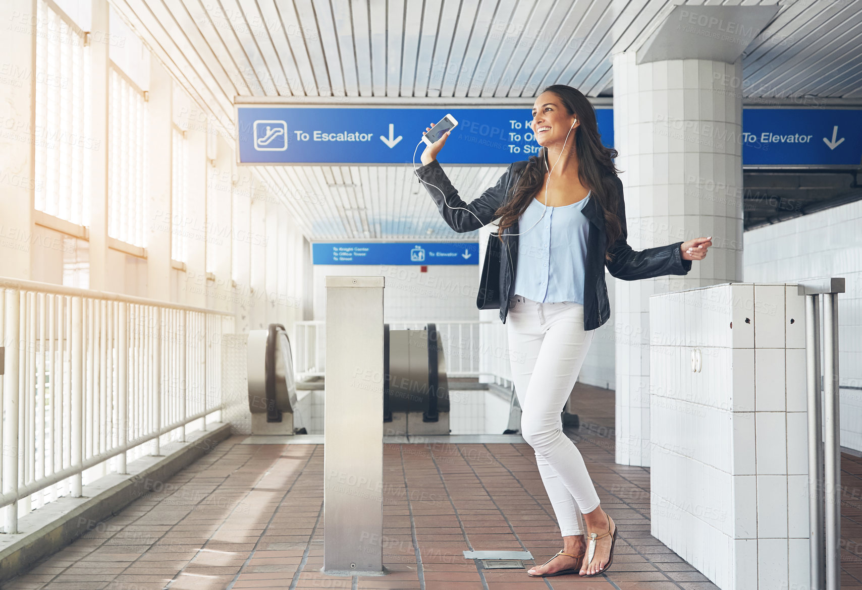 Buy stock photo Shot of a young woman dancing to music on a phone in an urban setting