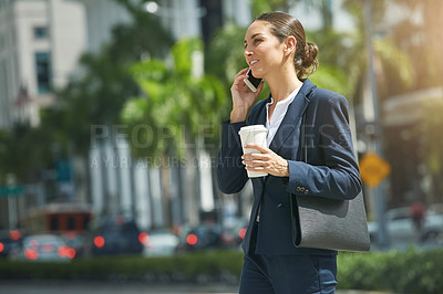 Buy stock photo Shot of a young businesswoman talking on her phone while out in the city