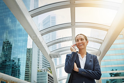 Buy stock photo Shot of a young businesswoman talking on her cellphone on her way to the office