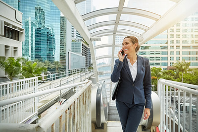 Buy stock photo Shot of a young businesswoman talking on her cellphone on her way to the office