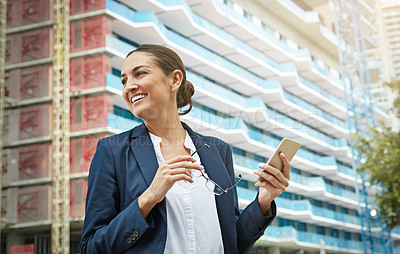 Buy stock photo Shot of a young businesswoman using her phone while out in the city