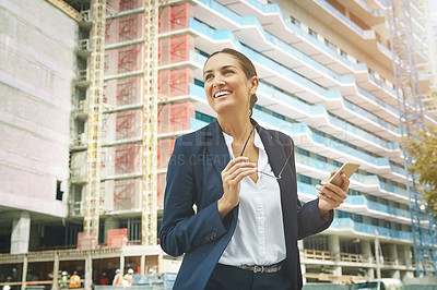 Buy stock photo Shot of a young businesswoman using her phone while out in the city