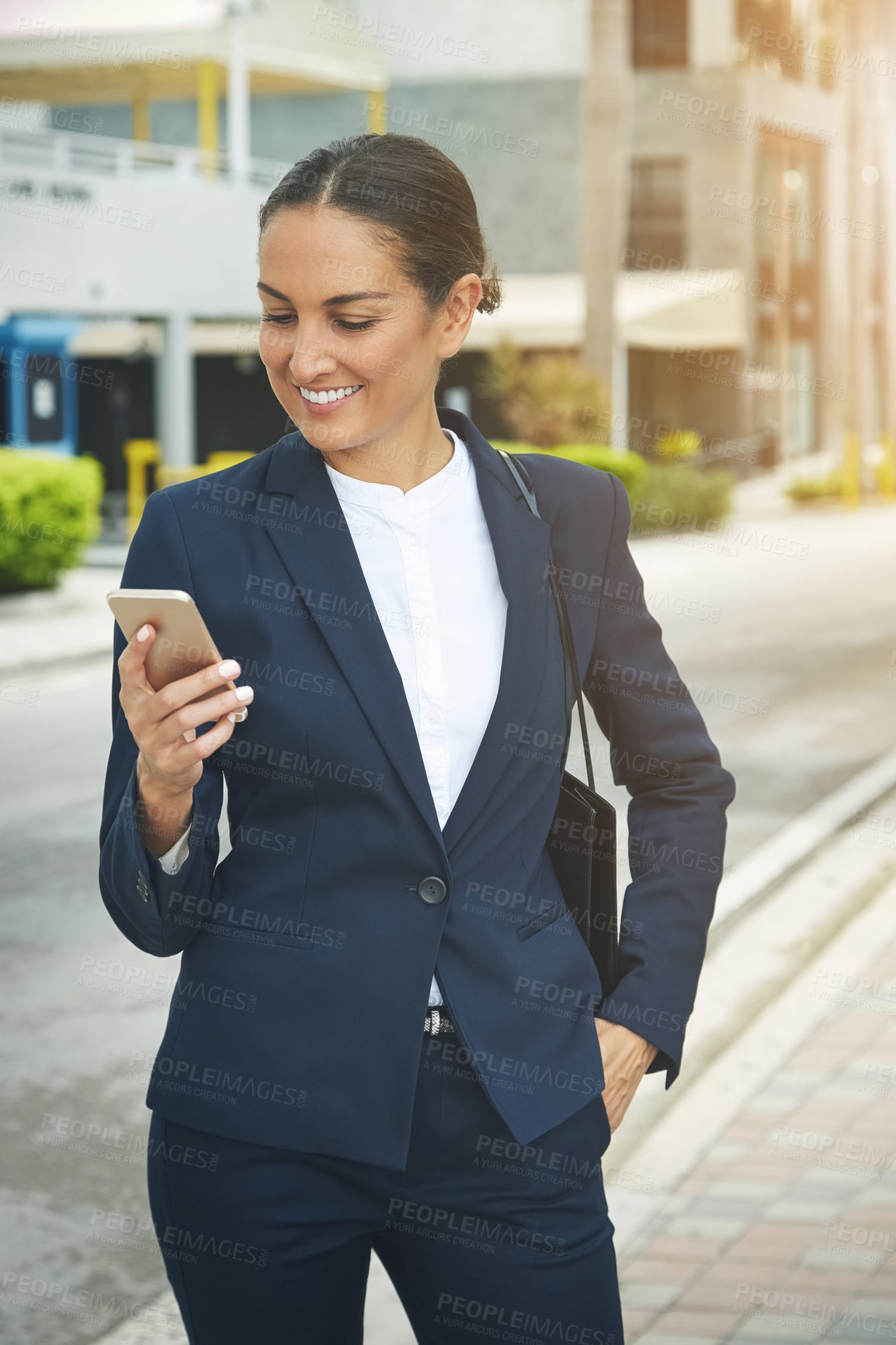 Buy stock photo Shot of a young businesswoman using her phone while out in the city