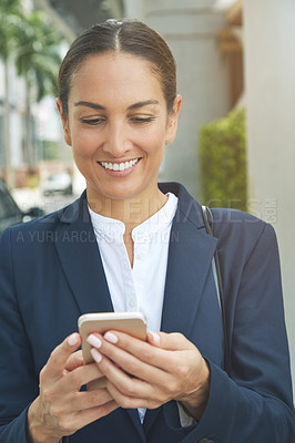 Buy stock photo Shot of a young businesswoman using her phone while out in the city