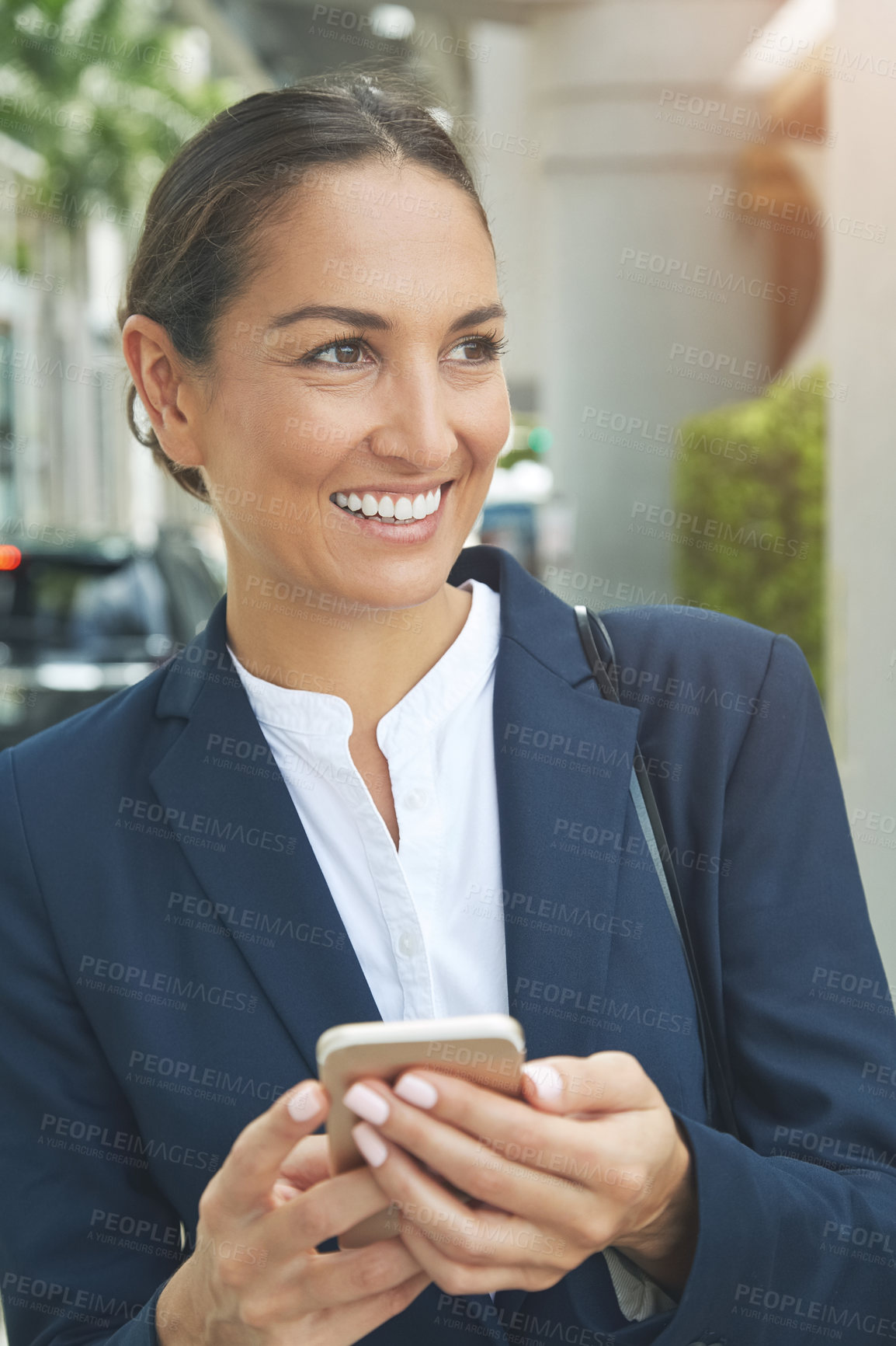 Buy stock photo Shot of a young businesswoman using her phone while out in the city