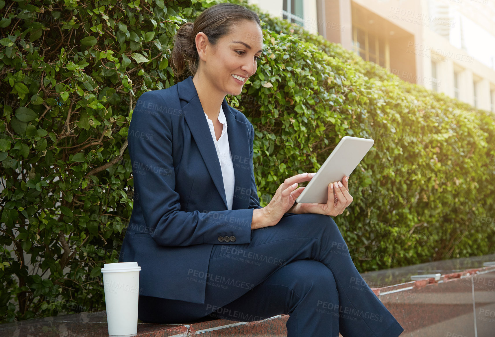 Buy stock photo Shot of a young businesswoman using her digital tablet while out in the city