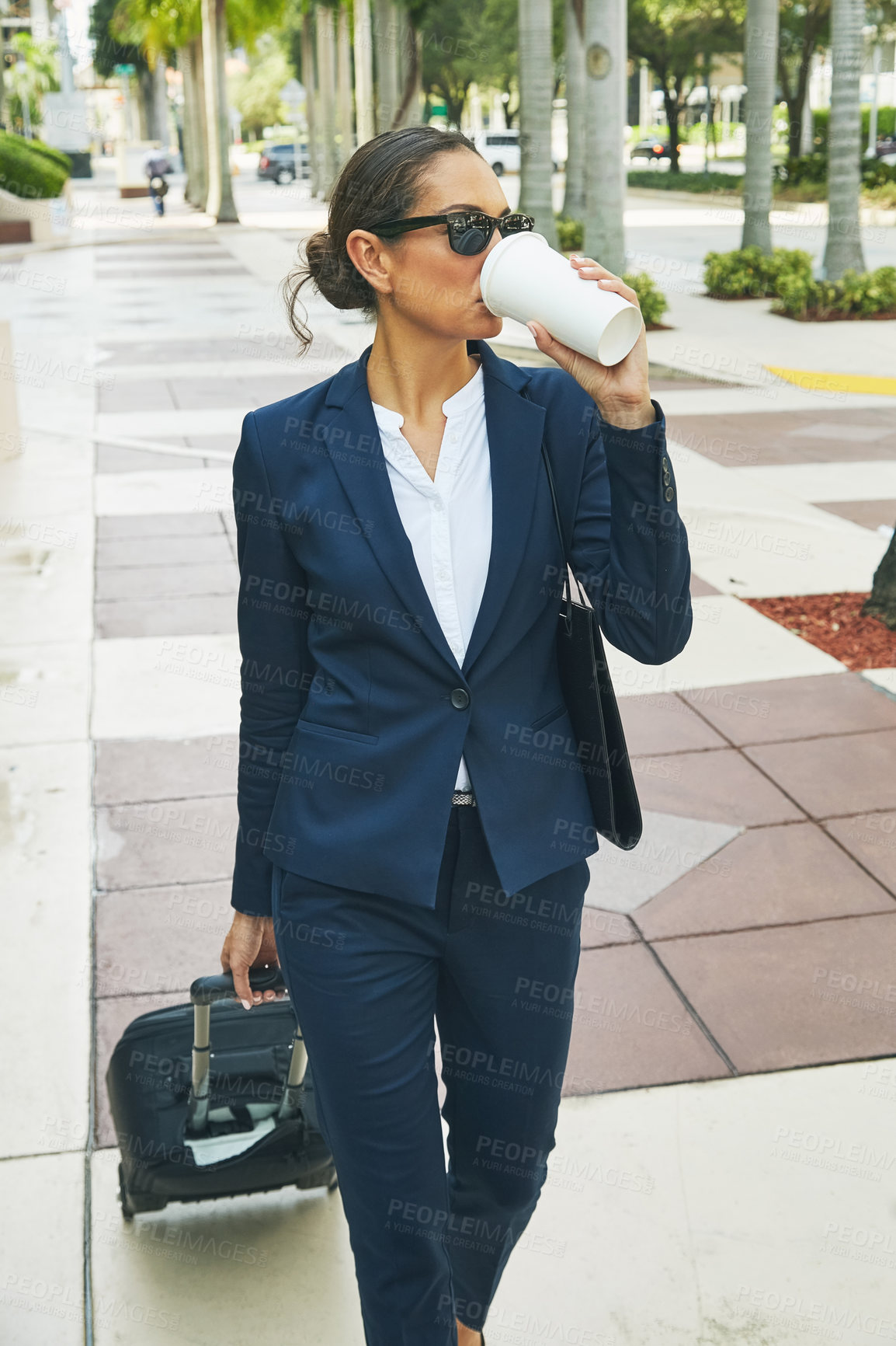 Buy stock photo Shot of a young businesswoman drinking coffee on the move in the city