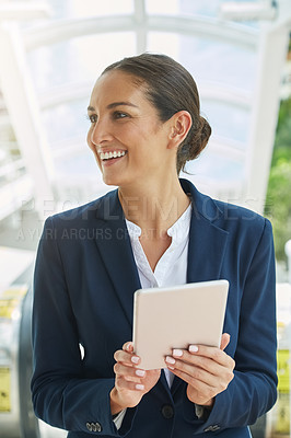 Buy stock photo Shot of a young businesswoman using a digital tablet on her way to the office