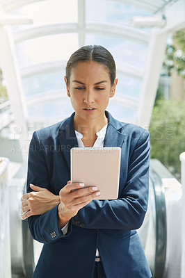 Buy stock photo Shot of a young businesswoman using a digital tablet on her way to the office