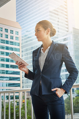 Buy stock photo Shot of a young businesswoman using a digital tablet on her way to the office