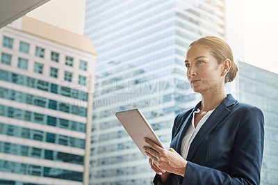 Buy stock photo Shot of a young businesswoman using a digital tablet on her way to the office