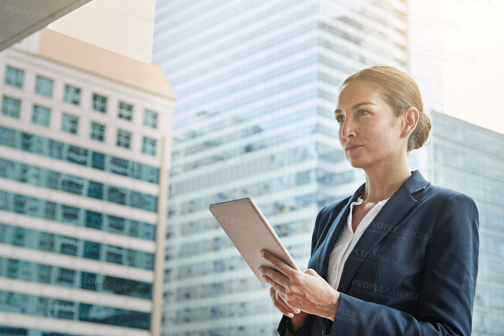 Buy stock photo Shot of a young businesswoman using a digital tablet on her way to the office