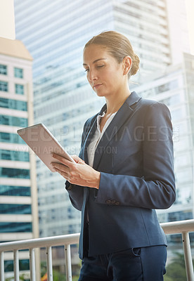 Buy stock photo Shot of a young businesswoman using a digital tablet on her way to the office