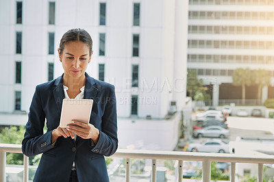 Buy stock photo Shot of a young businesswoman using a digital tablet on her way to the office