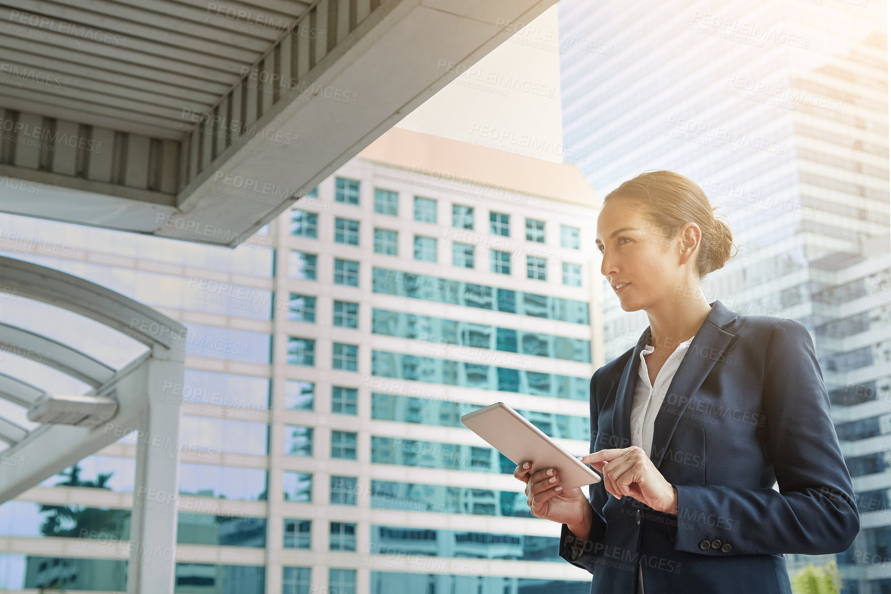 Buy stock photo Shot of a young businesswoman using a digital tablet on her way to the office