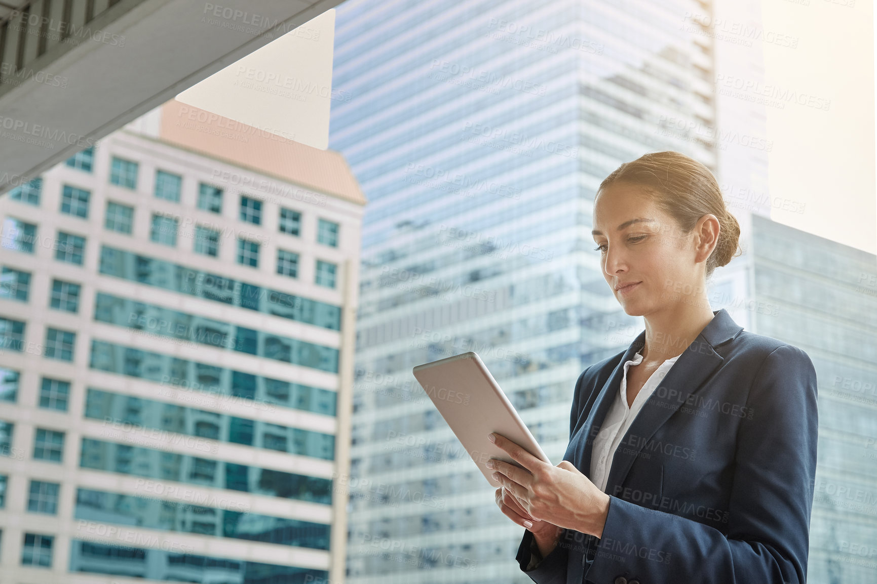 Buy stock photo Shot of a young businesswoman using a digital tablet on her way to the office