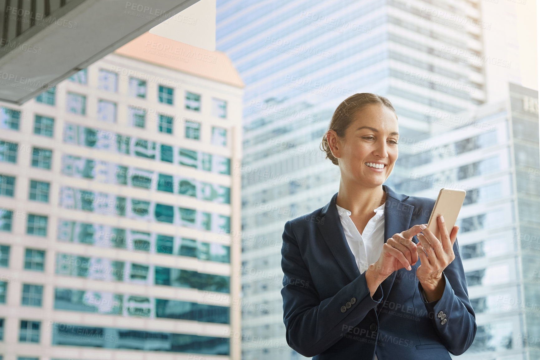 Buy stock photo Shot of a young businesswoman using a cellphone on the way to the office