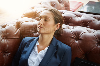 Buy stock photo Shot of a young businesswoman sleeping on a sofa