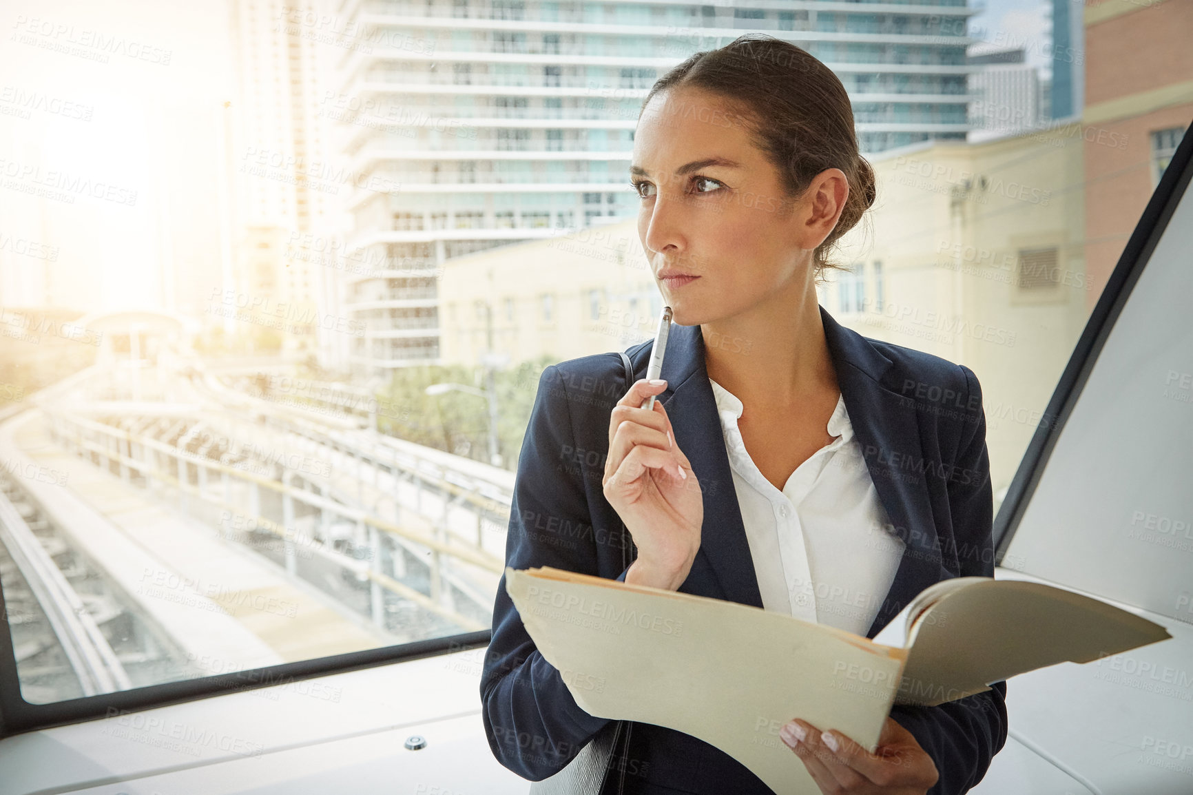 Buy stock photo Shot of a young businesswoman reading paperwork on her way to the office