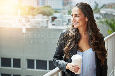 Buy stock photo Shot of a young woman holding a cup of coffee in an urban setting