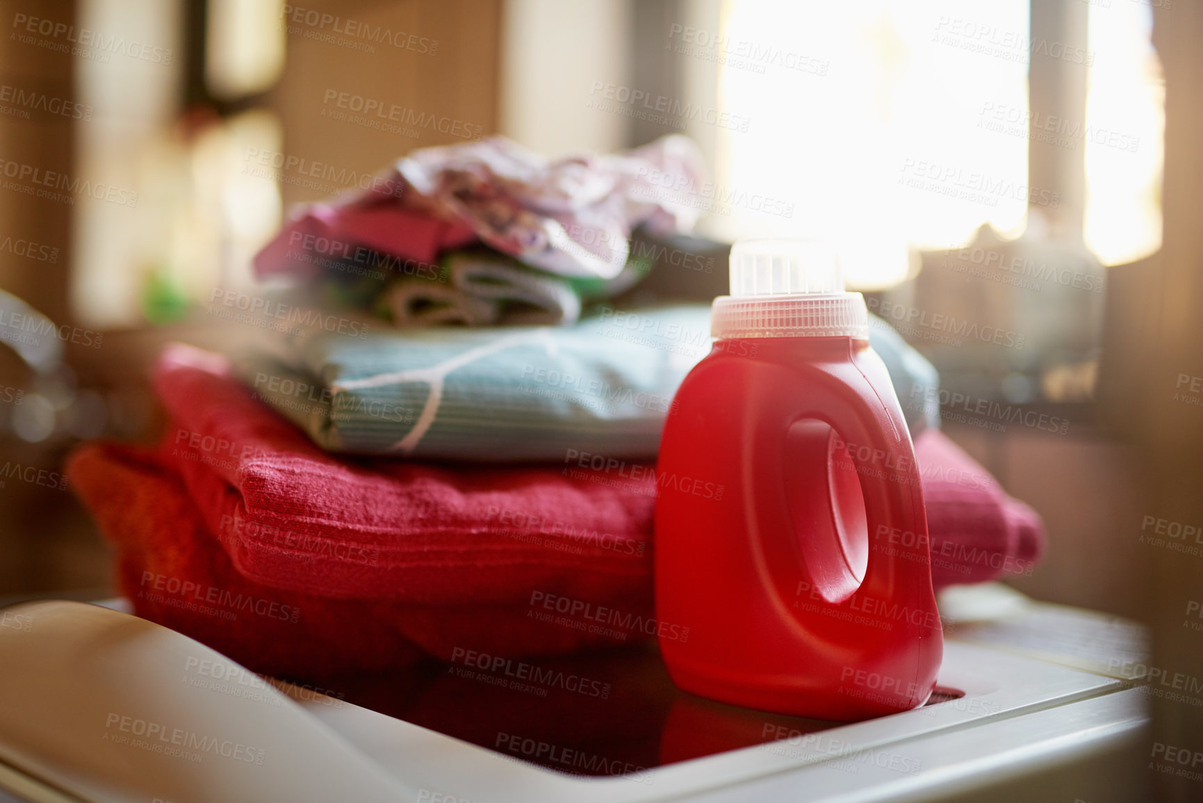 Buy stock photo Shot of a bottle of detergent and a pile of laundry on top of a washing machine