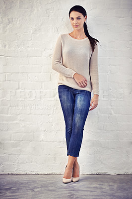Buy stock photo Shot of a casually dressed young woman standing against a brick wall