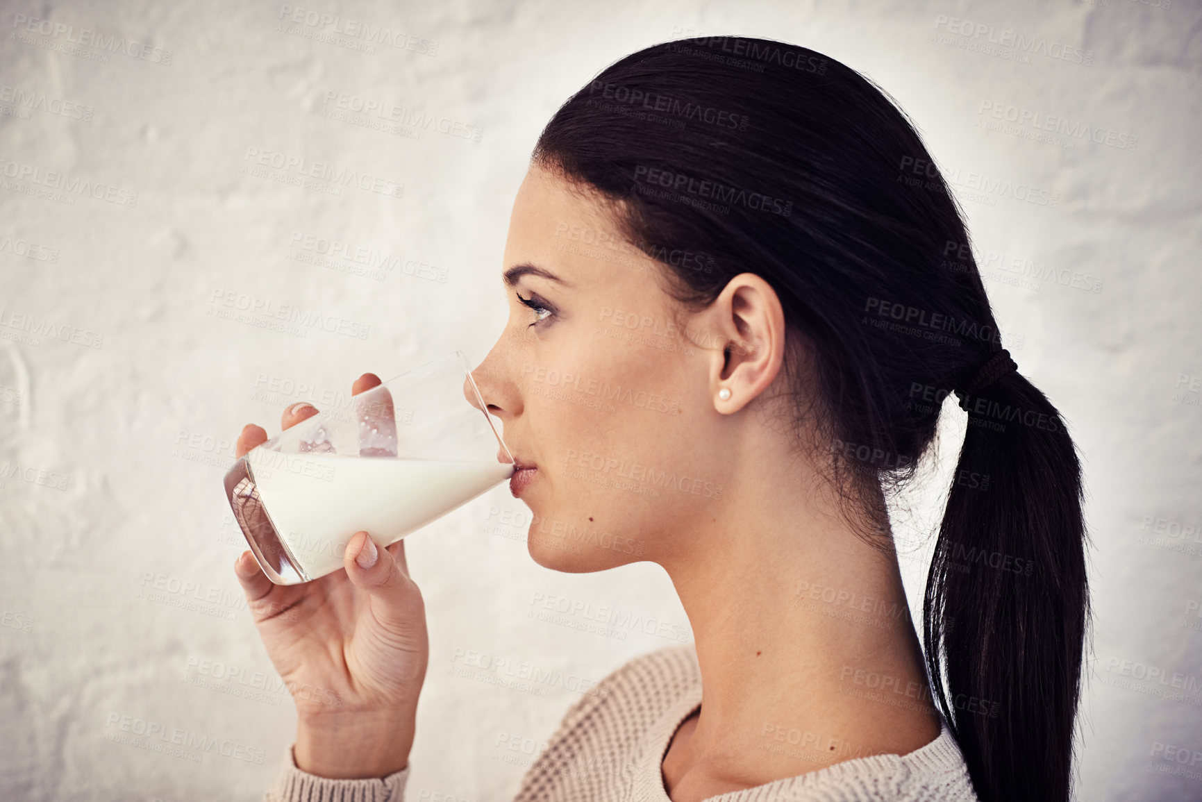 Buy stock photo Profile shot of a young woman drinking a glass of milk