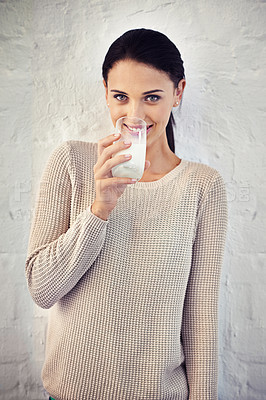 Buy stock photo Portrait of a young woman drinking a glass of milk